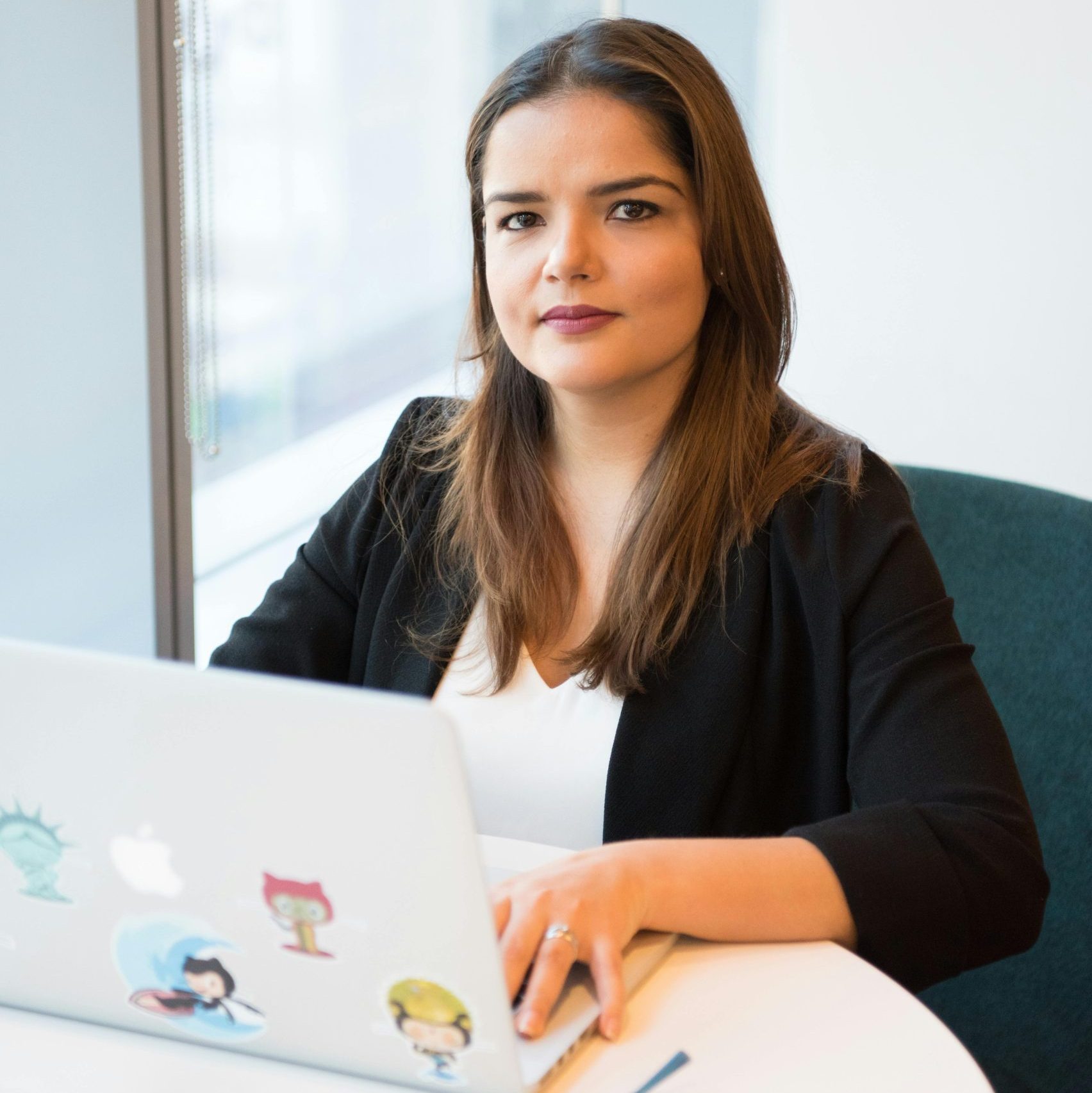 Confident businesswoman using laptop for remote work in a stylish office setting.